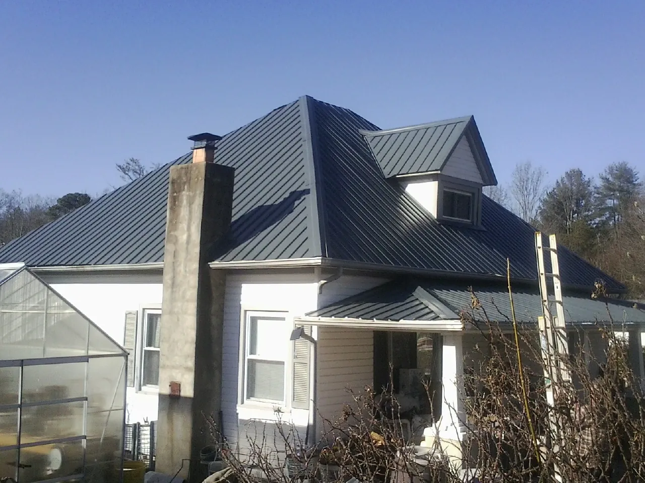 Dark blue standing seam metal roof on a white farmhouse with dormer — Slate & Tile Roof Repair by Roofing Brothers in Yakima