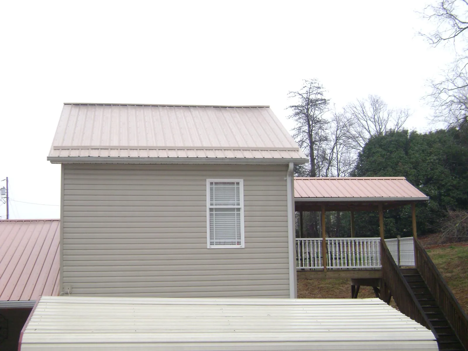 Tan metal roofs on a two story addition and attached porch, from a Roof Replacement job in Yakima