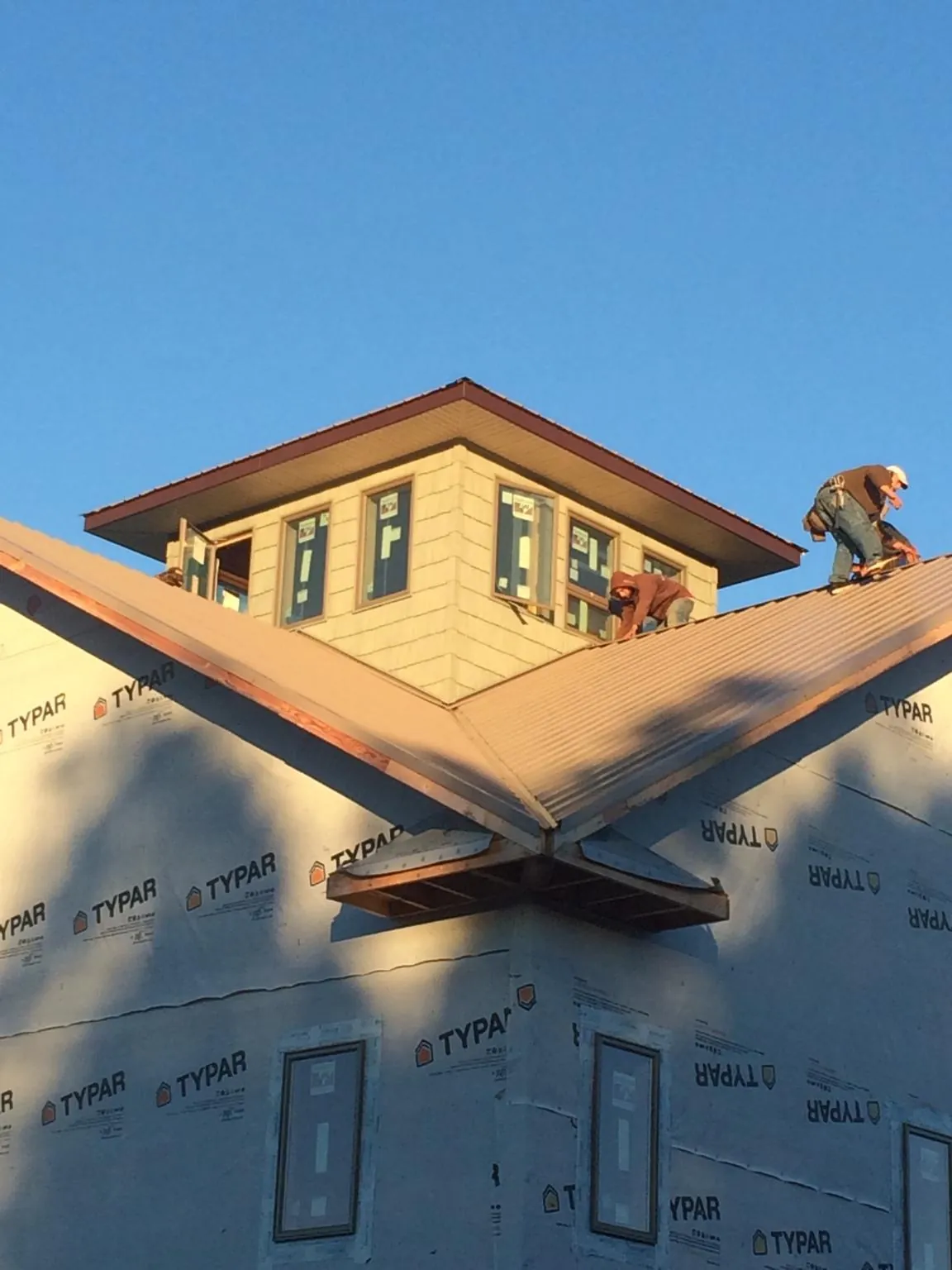Roofers working around a rooftop cupola on a new metal roof at sunset — Roof Waterproofing in Yakima by Roofing Brothers